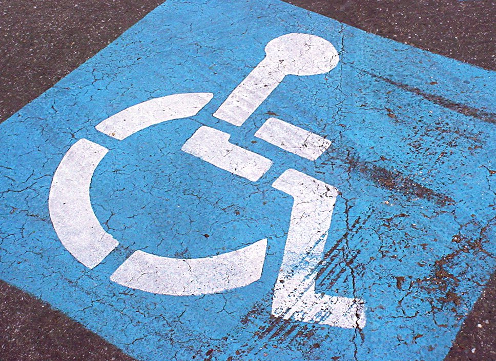 an image of a blue handicap parking sign painted on concrete