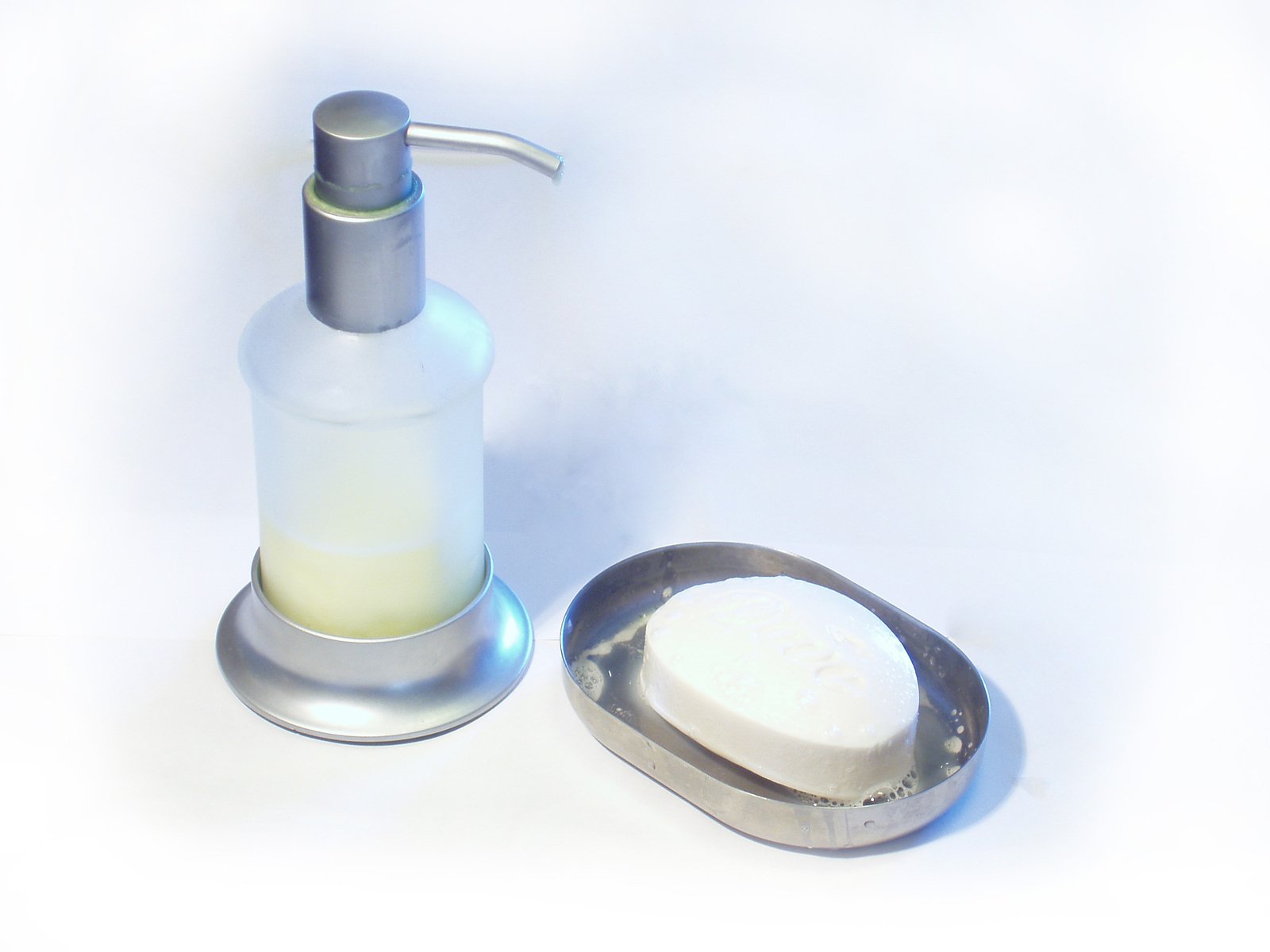 a white soap dispenser with a small scoop beside it