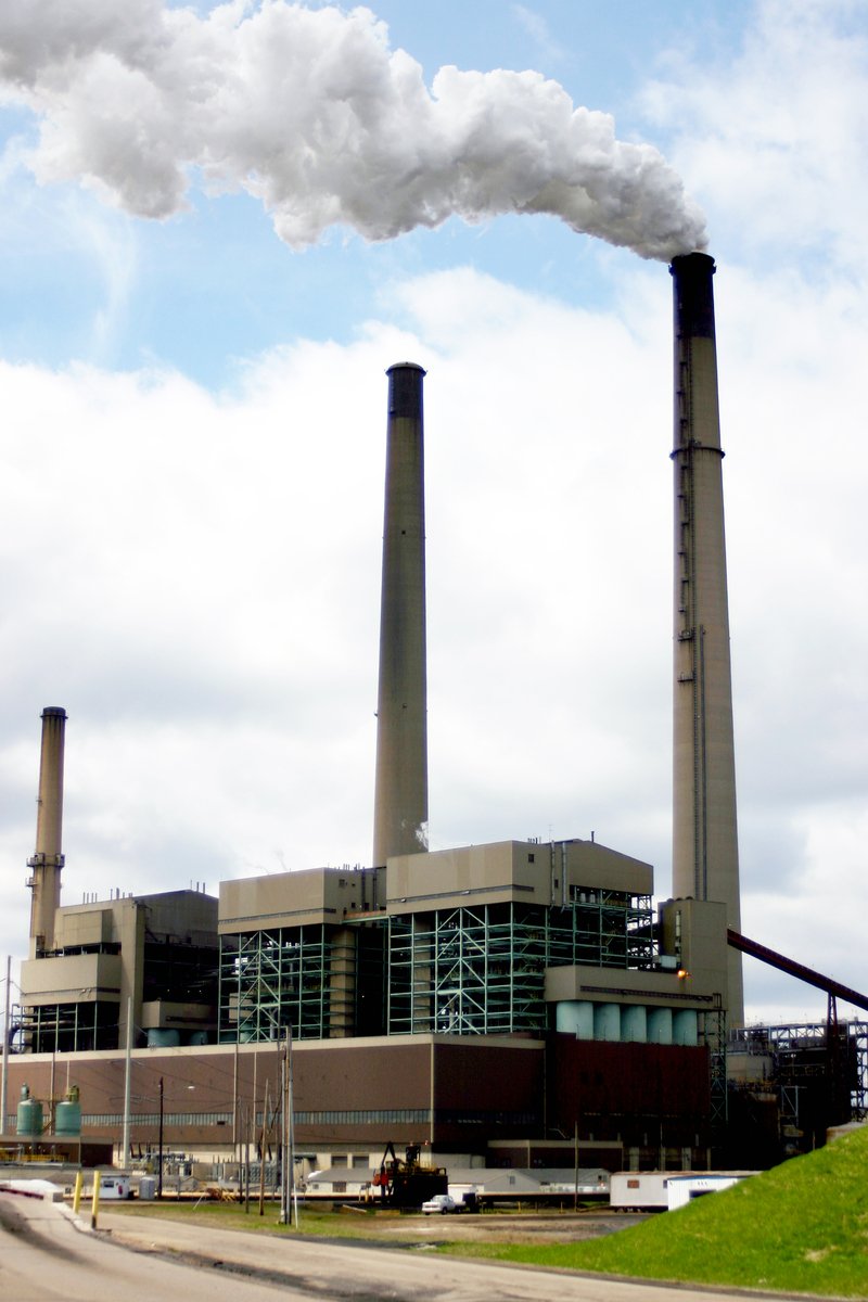 two smokestacks in front of a power plant emits from the stacks