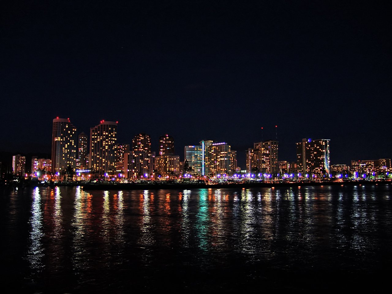 a city lights up the night sky over water