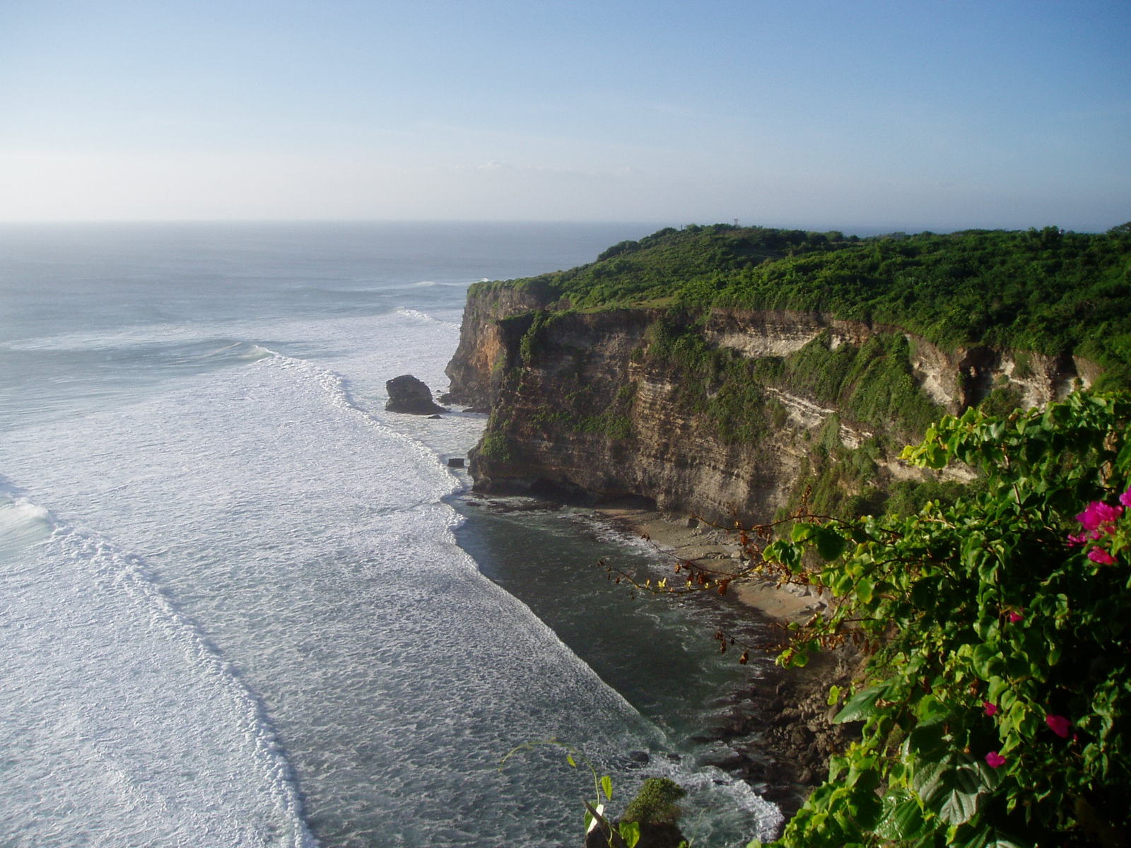 the ocean is next to the green hillside