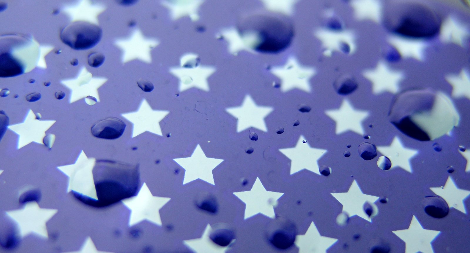 closeup view of water droplets and stars on purple paper