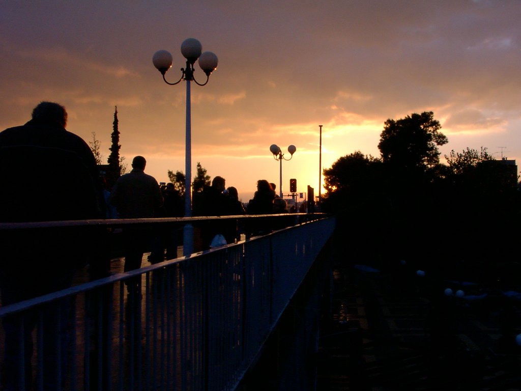 people walk on the walkway and watch the sun set