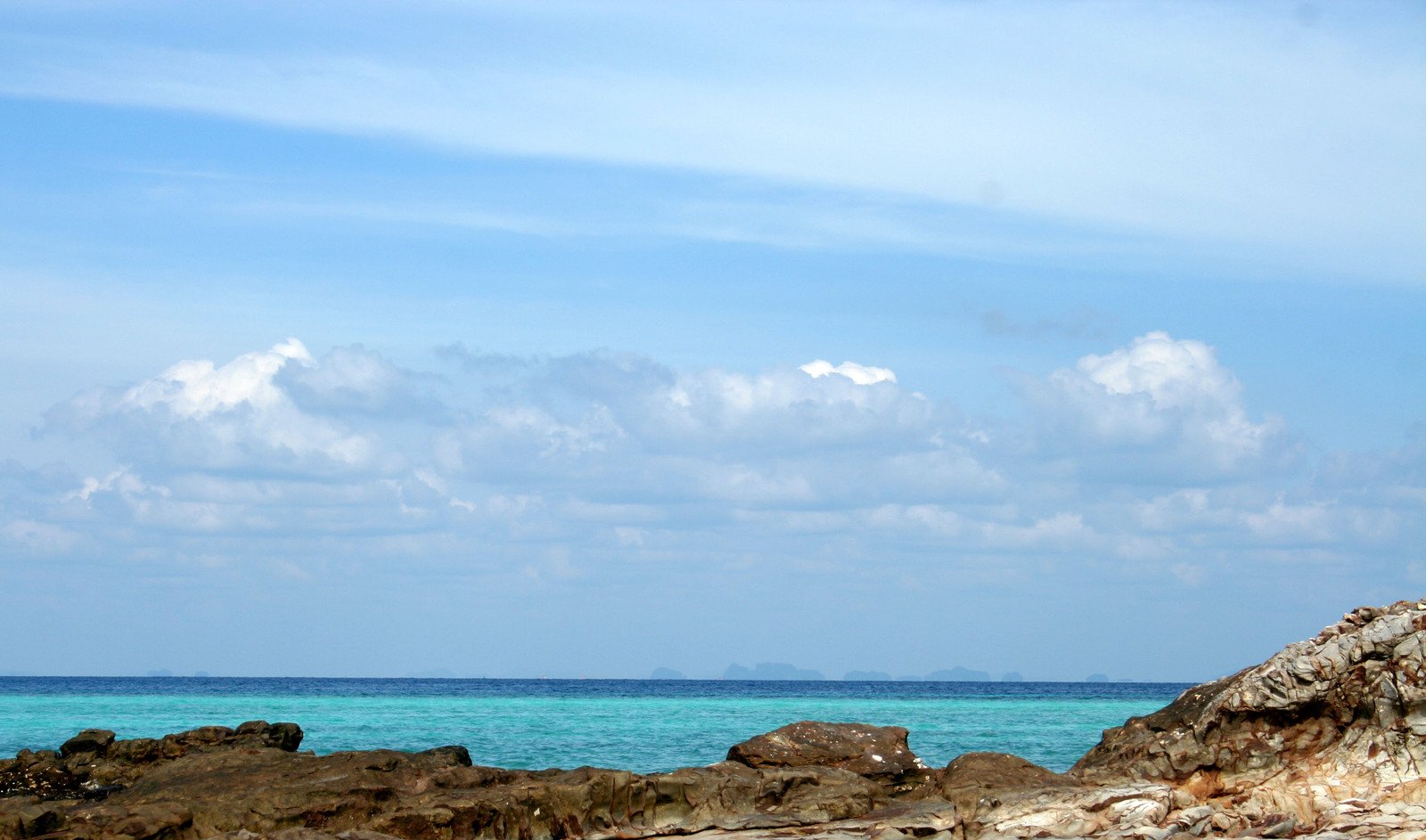 two people stand on rocks, looking out to sea