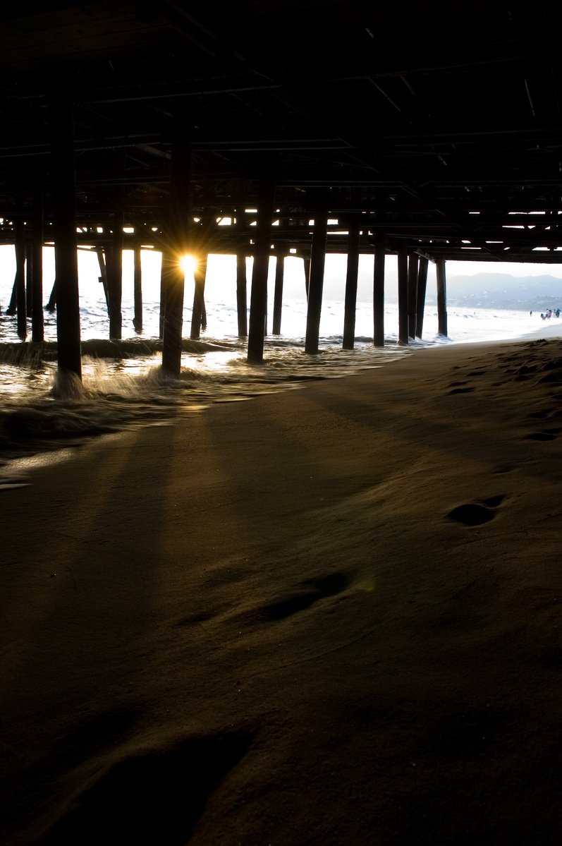 a person standing on the beach next to a pier