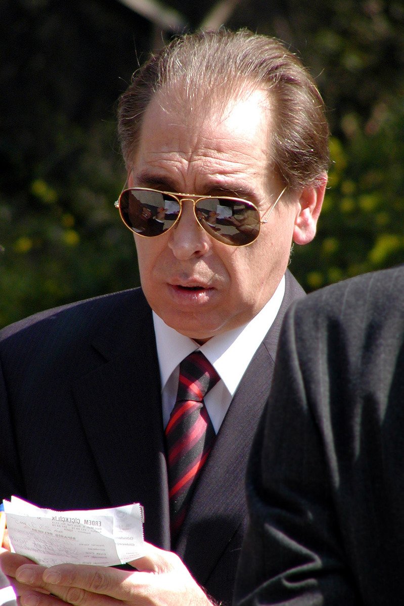 a man wearing sunglasses and a suit sitting outside