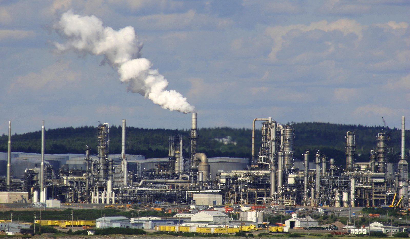 a large refinery with several buildings and trees in the background