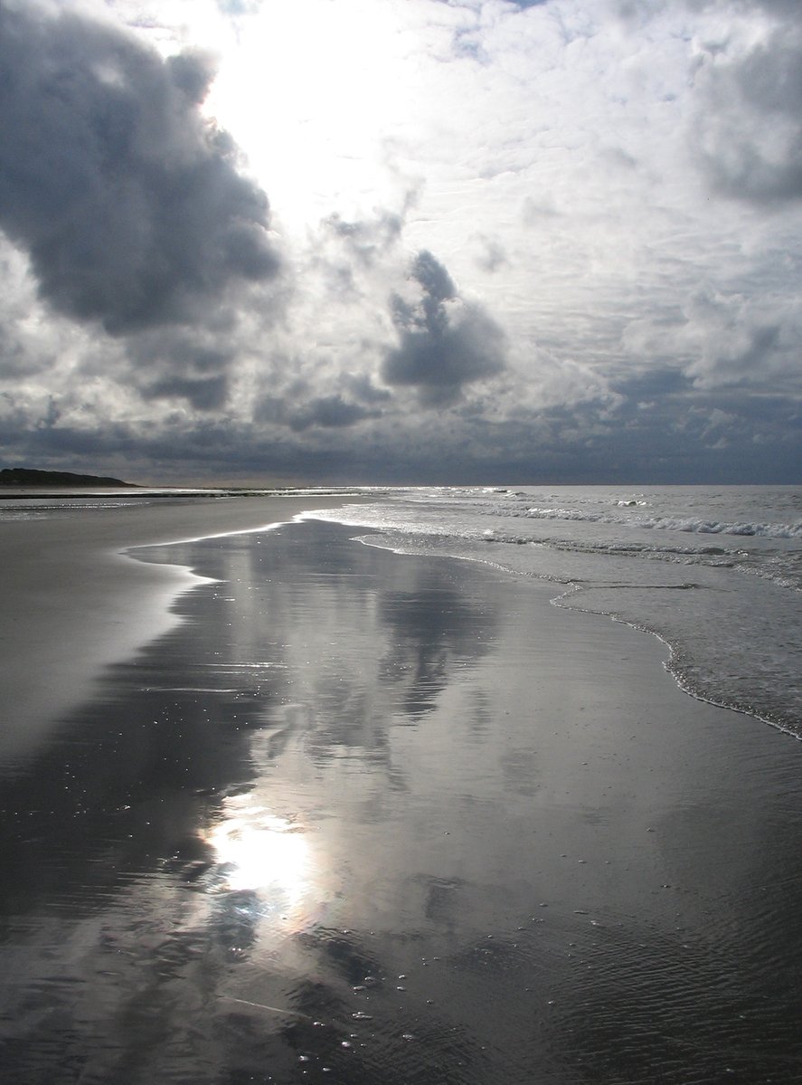 the sun shines in between the clouds over the water at the beach