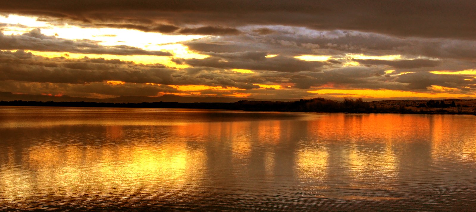 sunset reflected in the water with dark clouds
