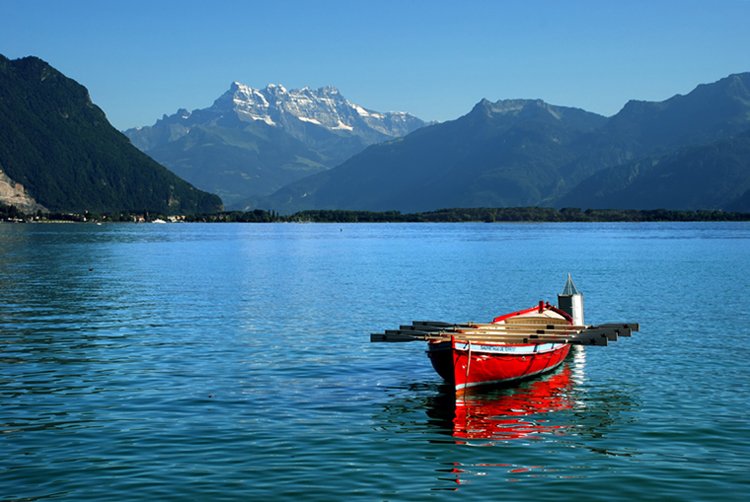 a red boat in the middle of a calm lake