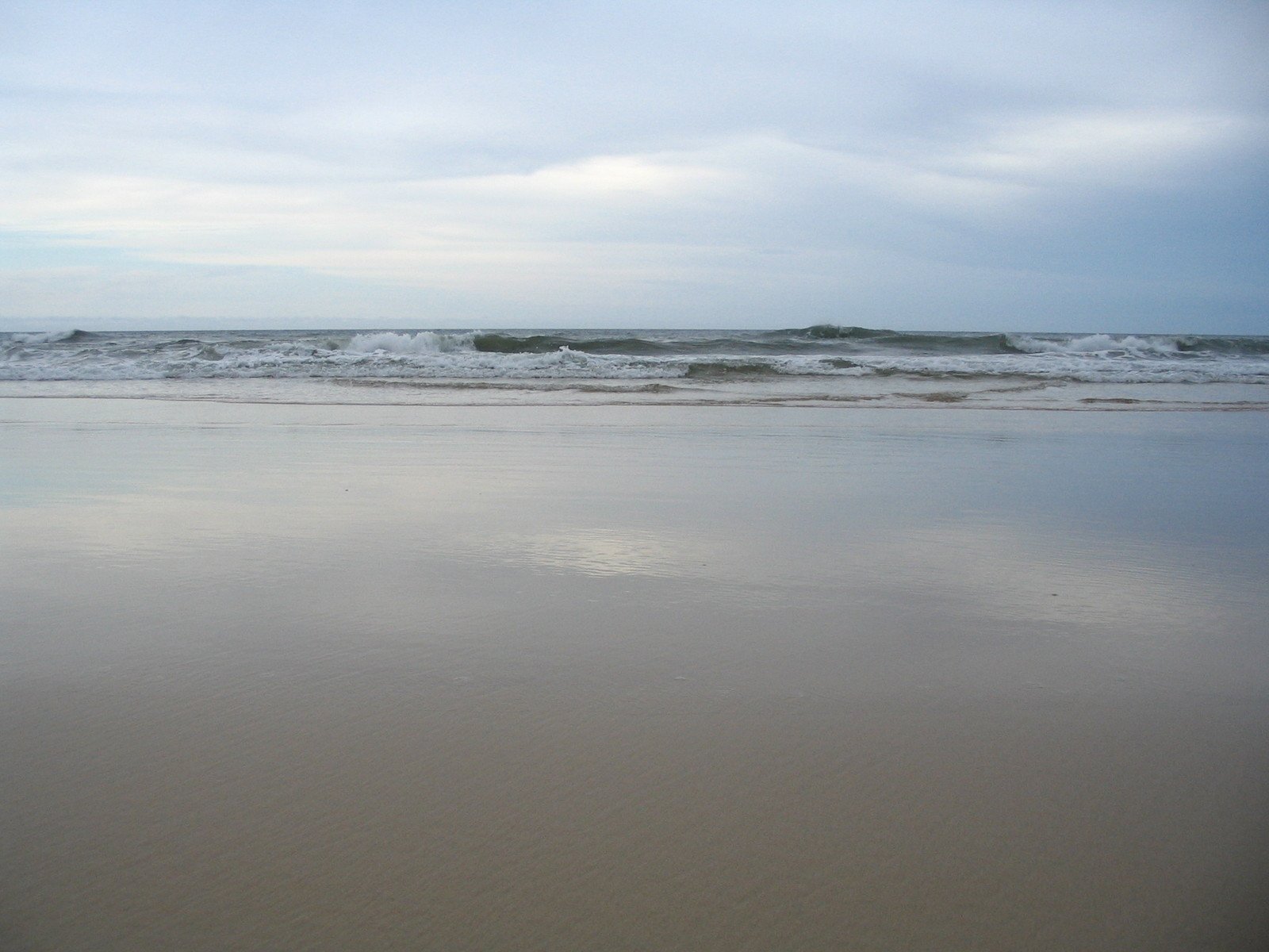 an empty sandy beach with a lone surf board