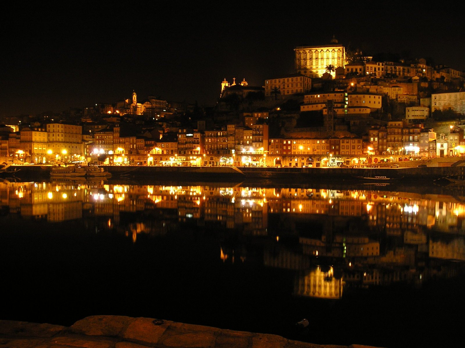 the night view of buildings on a hill from across a lake