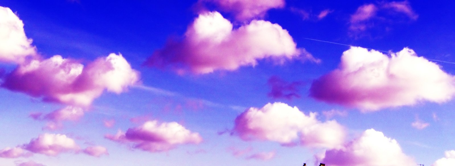 white fluffy clouds form a pinkish background as the plane flies in the sky