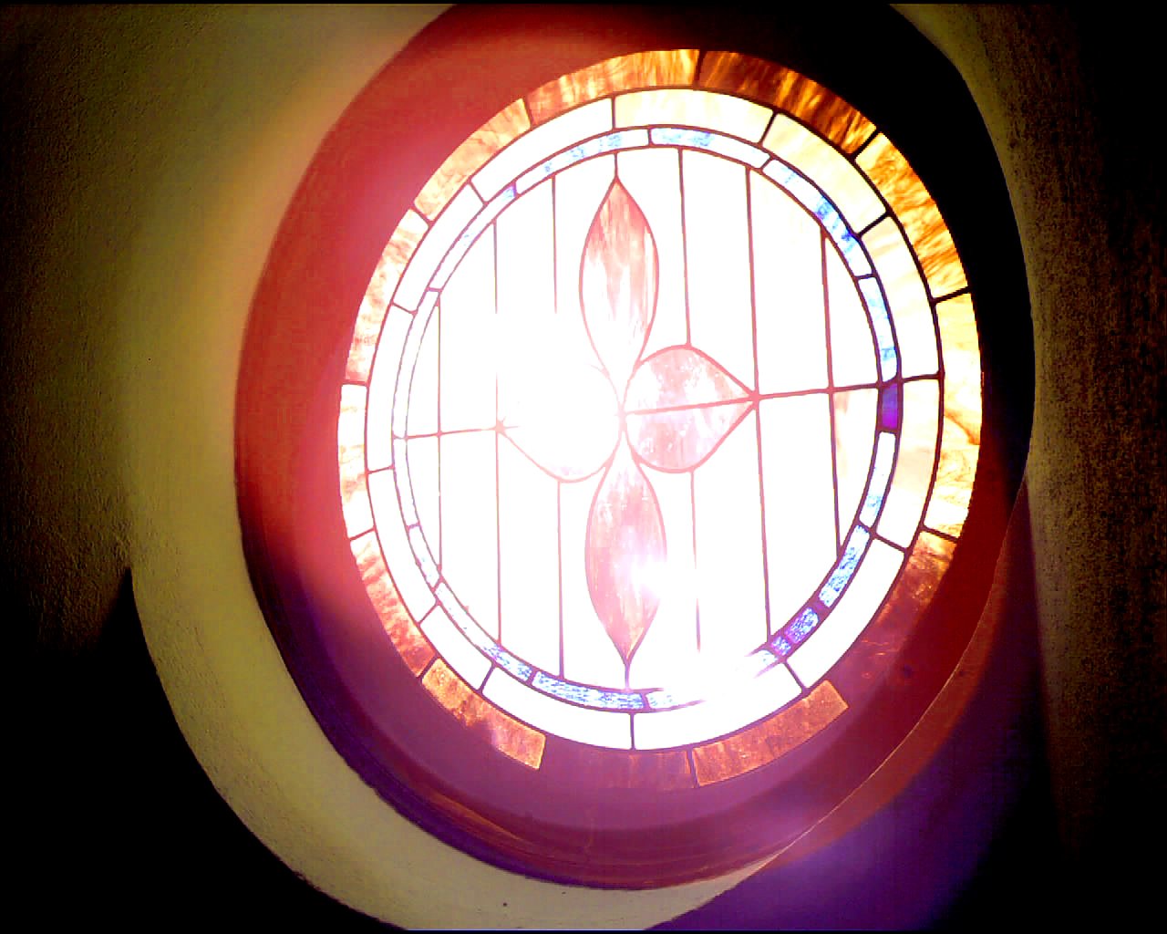 a red circular glass window with flowers in it