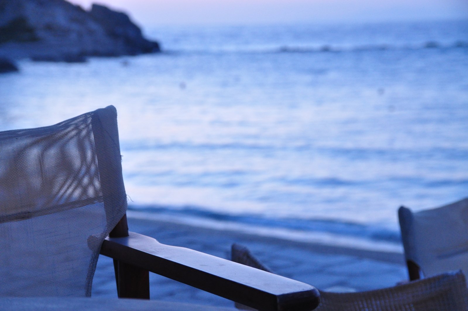 two chairs are on a beach near the water