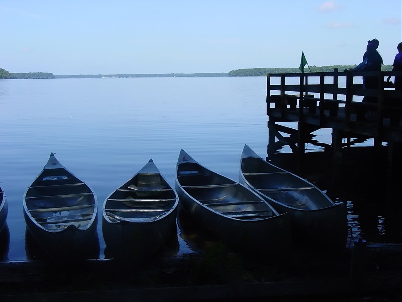 row boats sit in the water on a pier