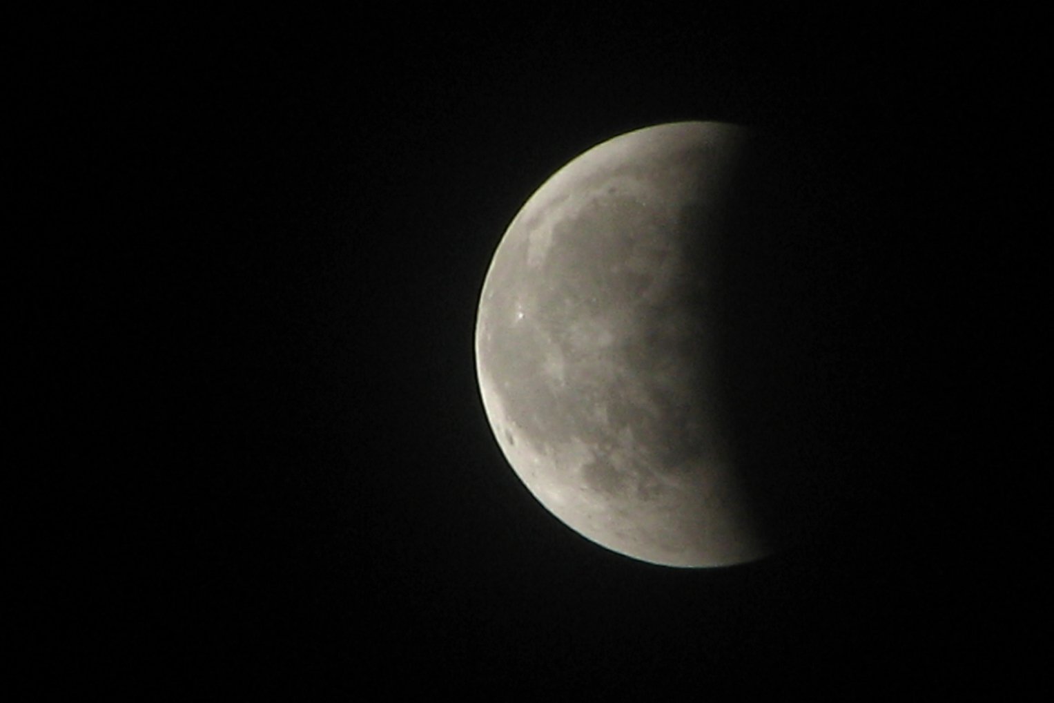 the moon can be seen in the black sky, almost beyond the bright light