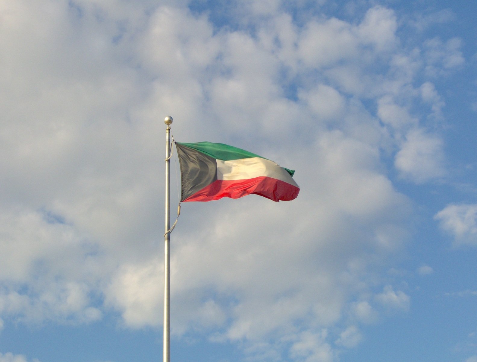 a flag on a pole against a cloudy blue sky