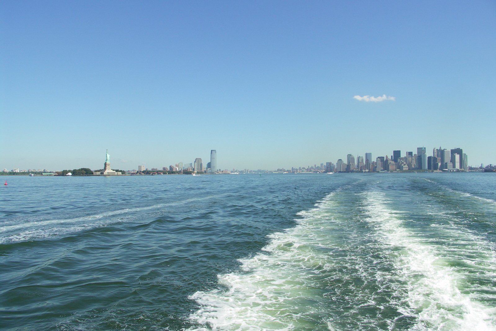 a boat traveling through the water with cityscape in the background