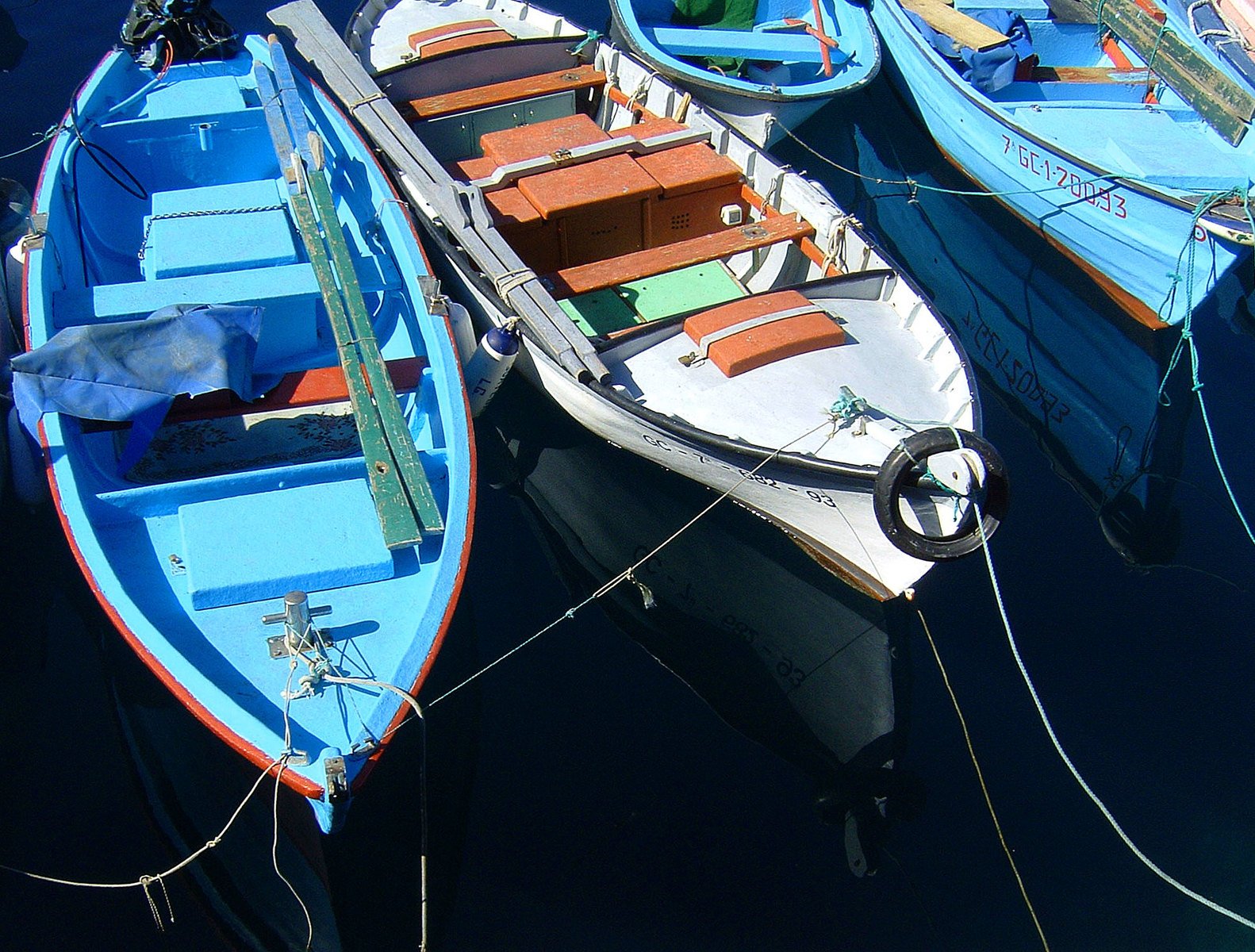 four small boats tied to a dock near each other