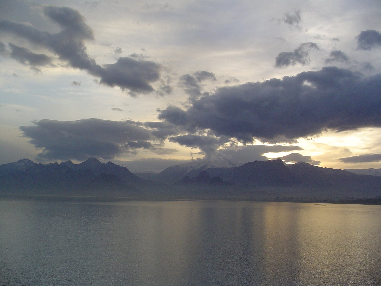 some dark clouds hanging over some mountains and water