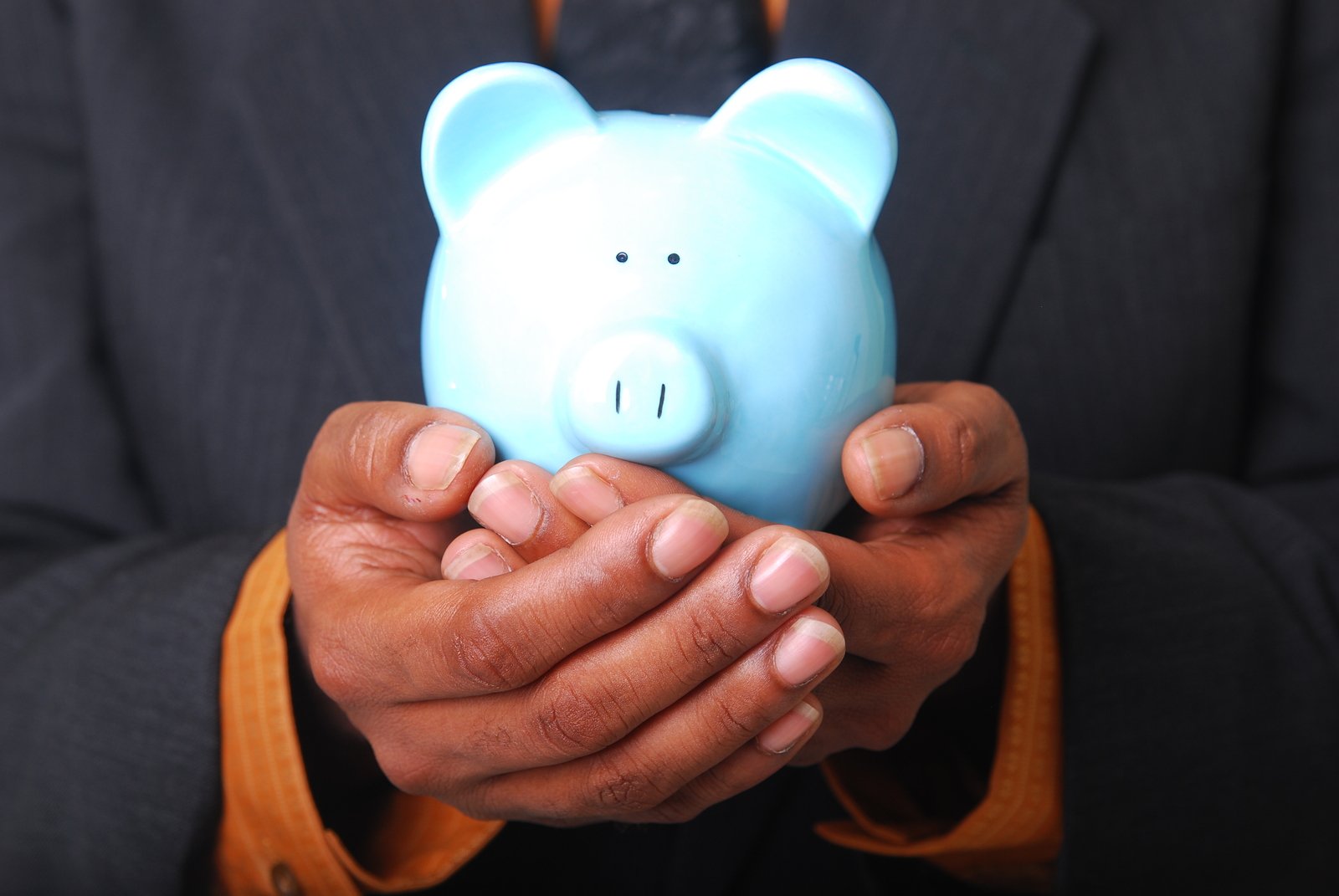 a man holding a piggy bank with his hands