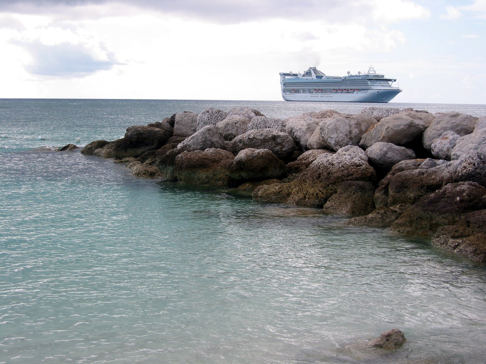 the cruise ship is anchored on the rocks by the ocean