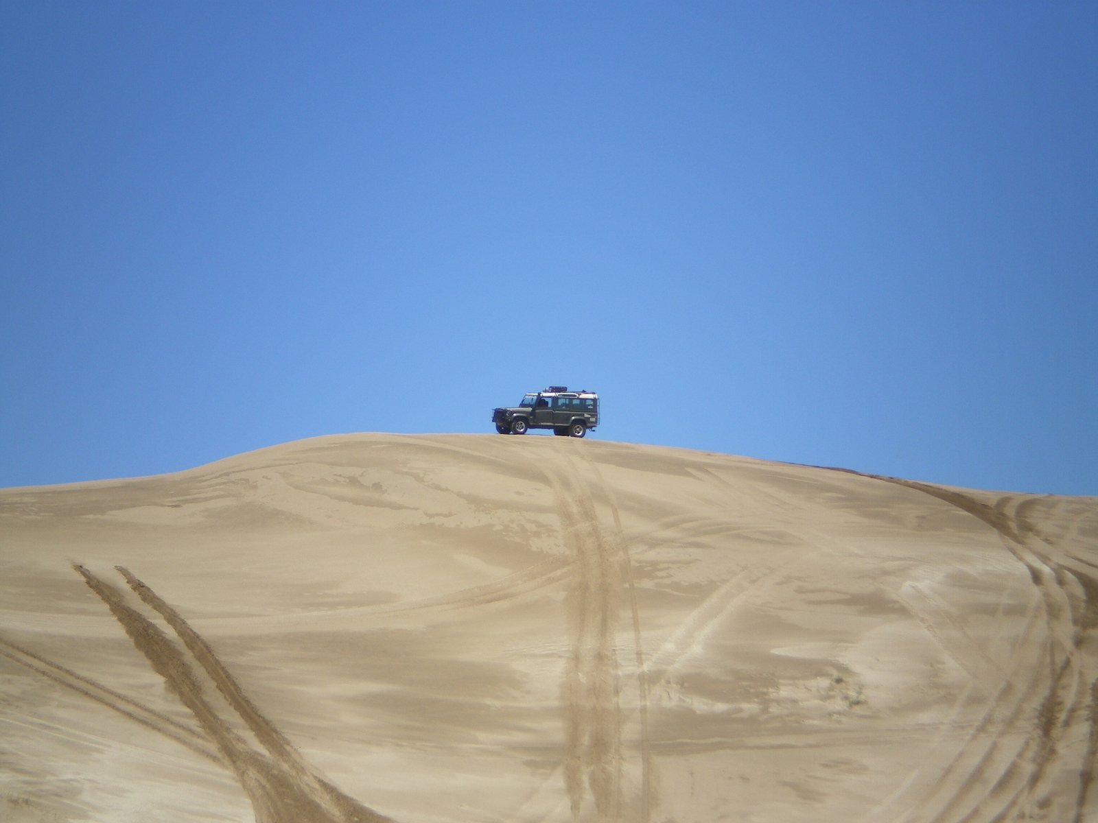 a blue truck driving through the sand dunes