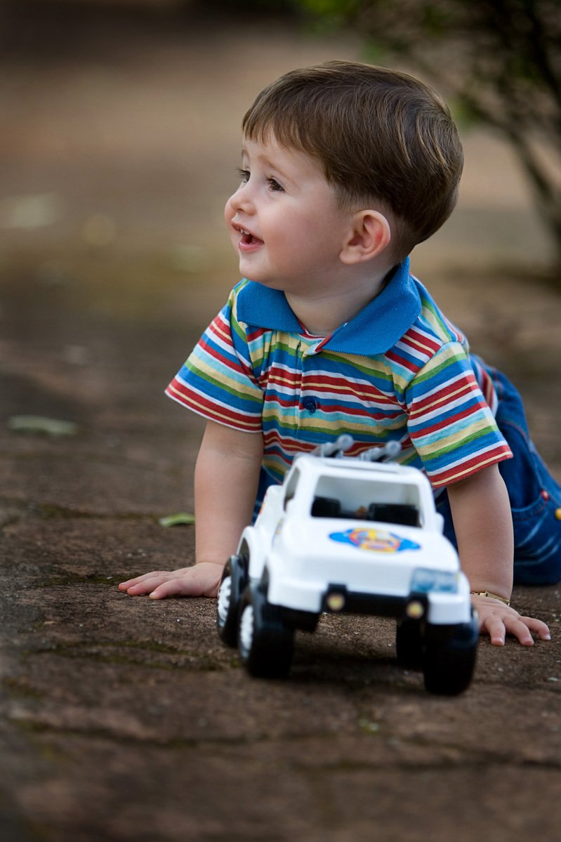 a baby boy on the ground playing with a toy car