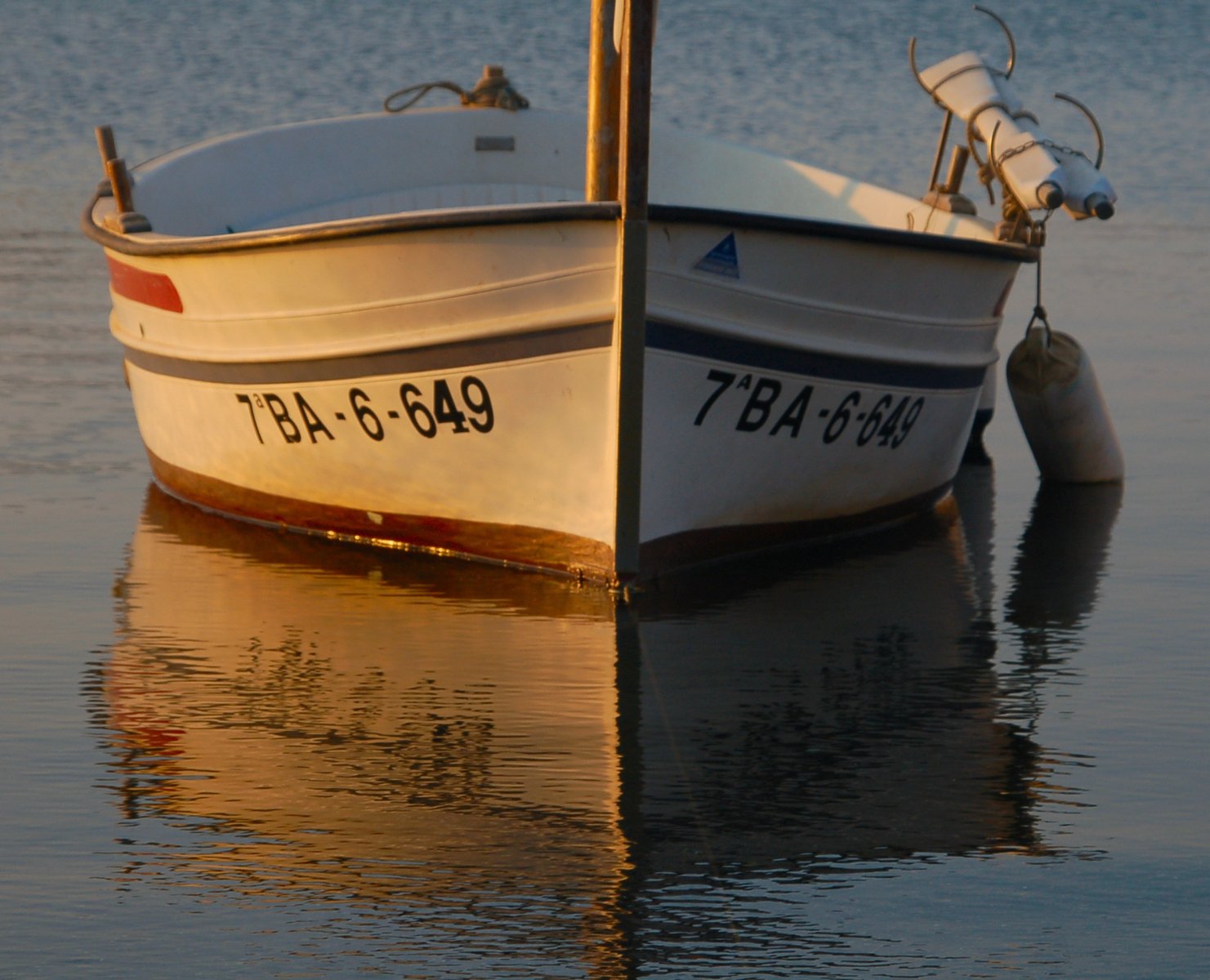 the small white boat is sitting on the water