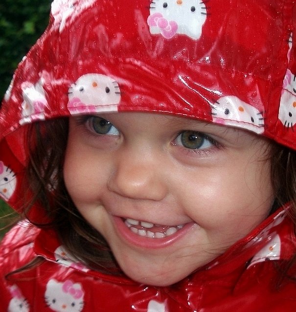 the little girl is all dressed up in a red hello kitty raincoat
