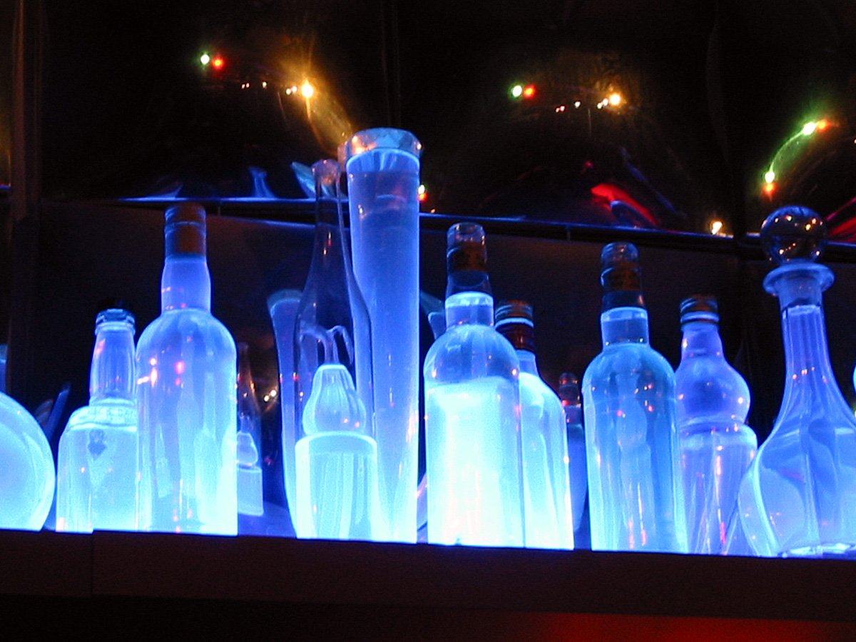 illuminated glass bottles lined up on shelves