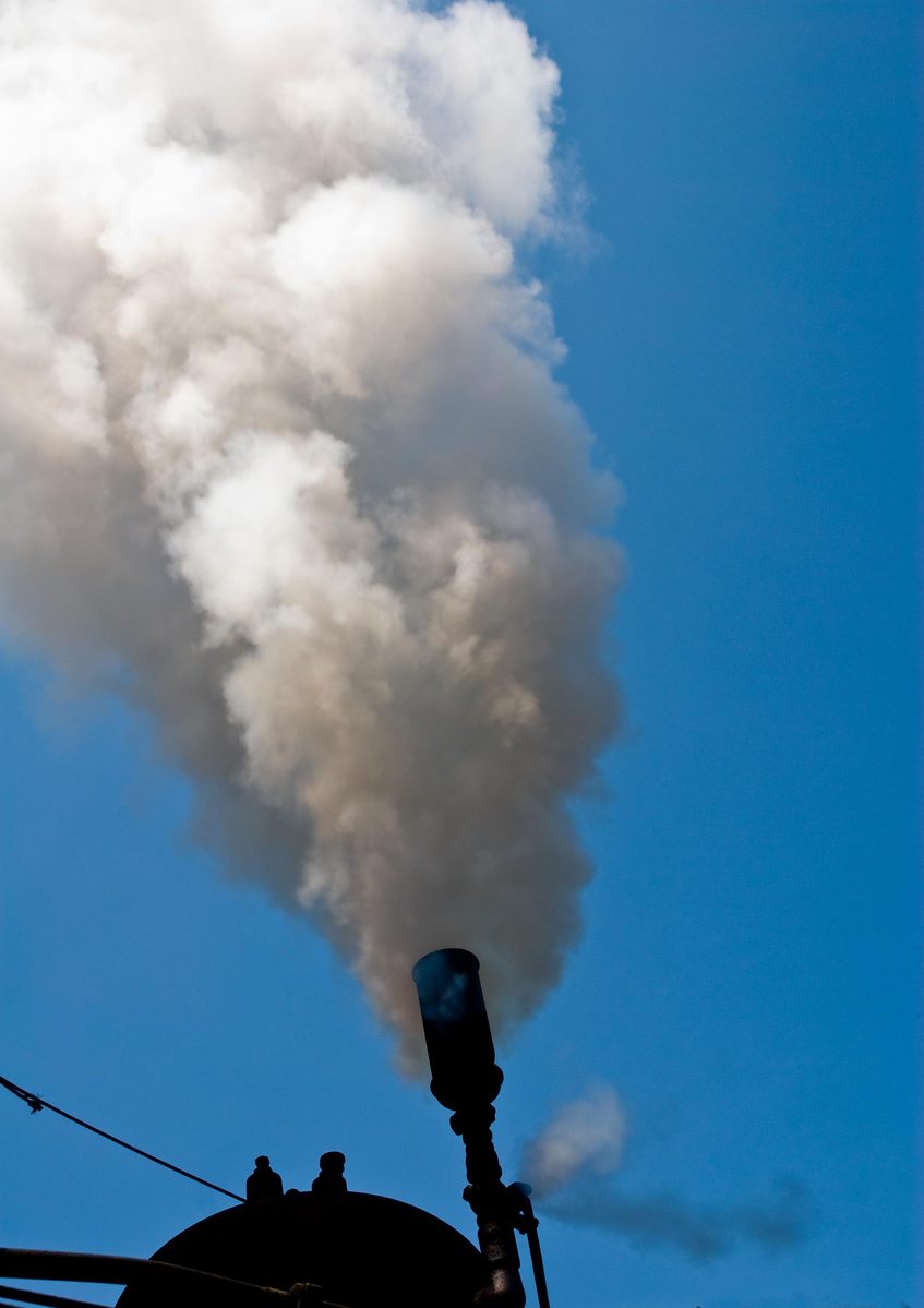 a smokestack emits steam into the sky