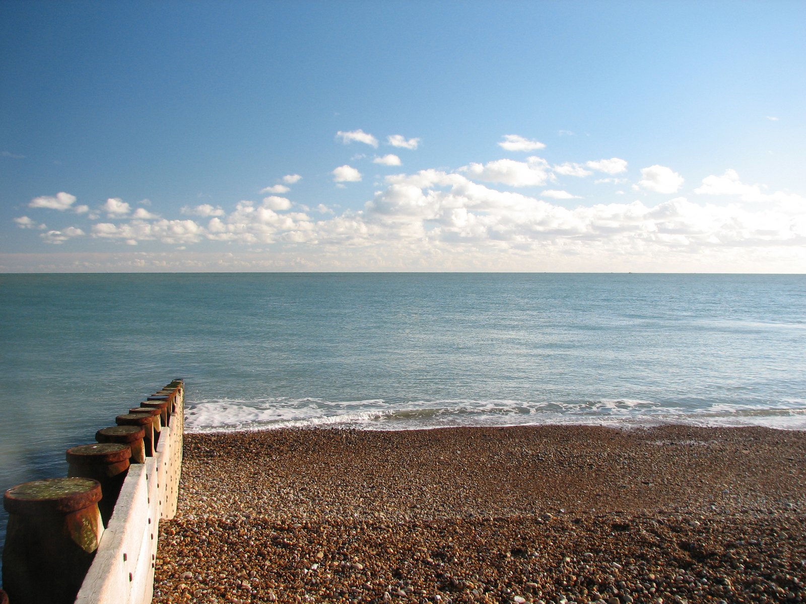 waves crash onto a beach as a pier stands on the beach