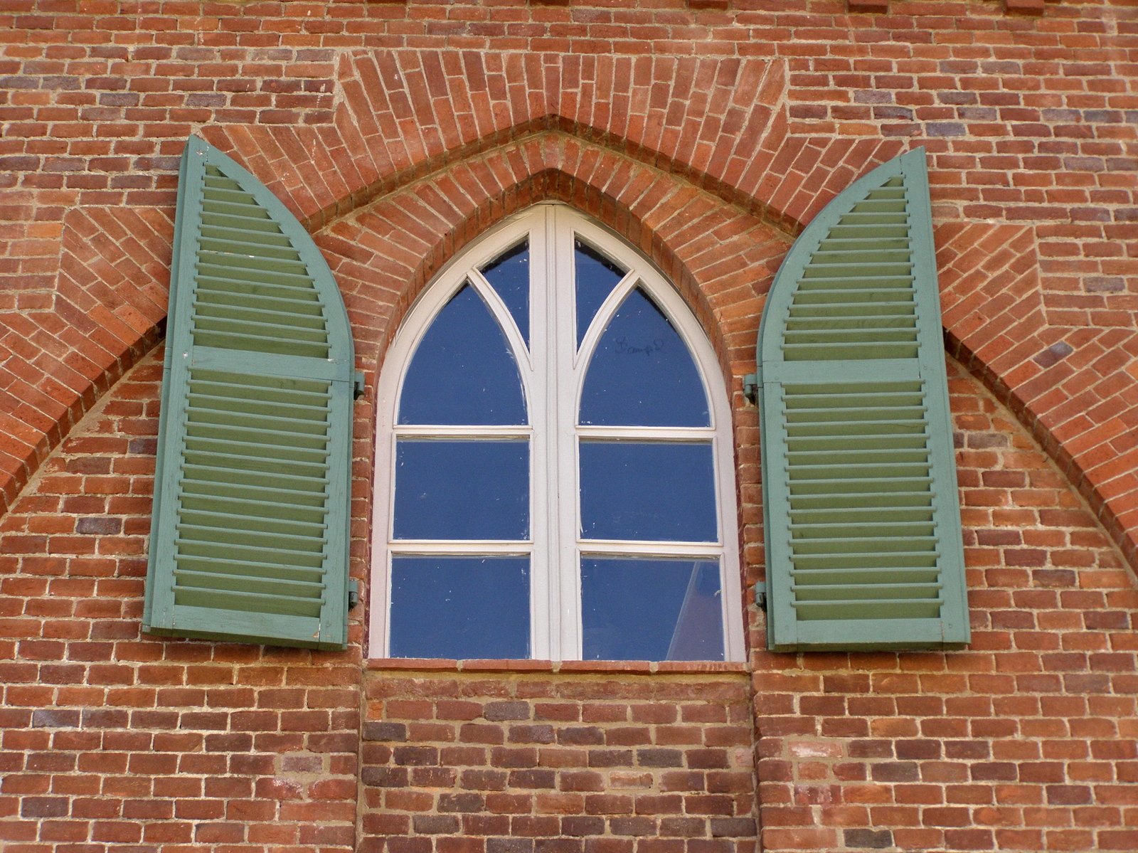 three green windows in a brick building