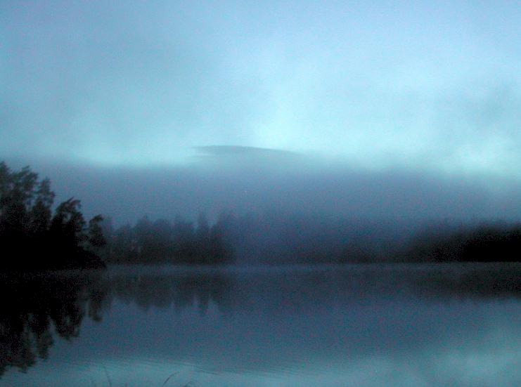 there is fog on the sky above a lake
