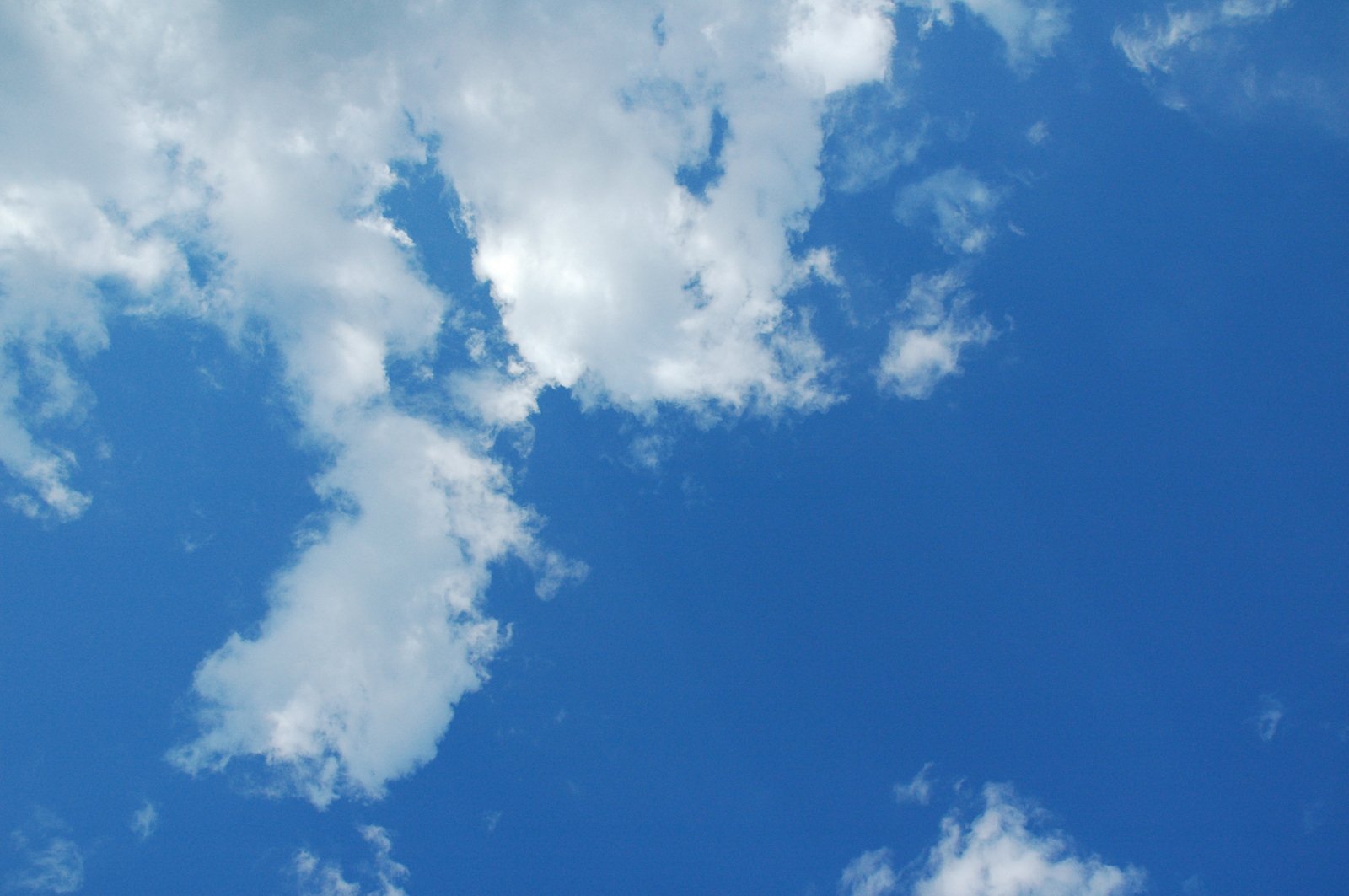 a large jet flying through a blue cloudy sky