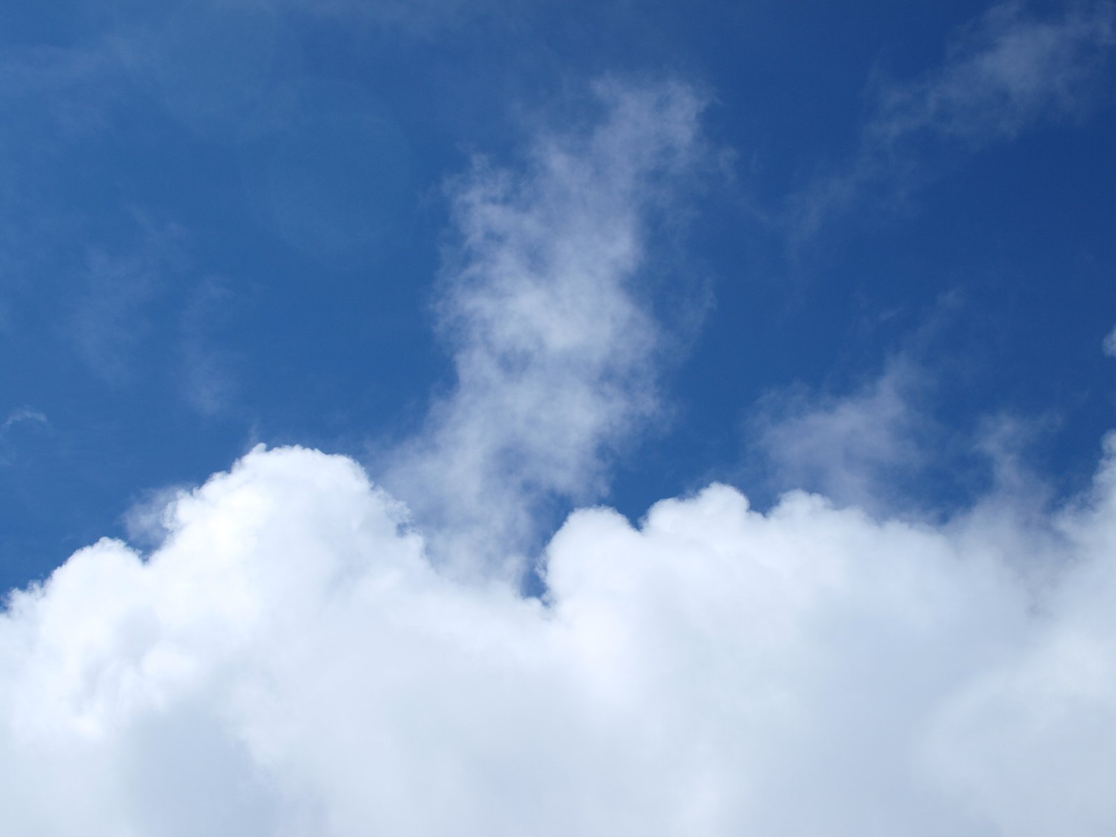 white clouds against a blue sky with an airplane in the background