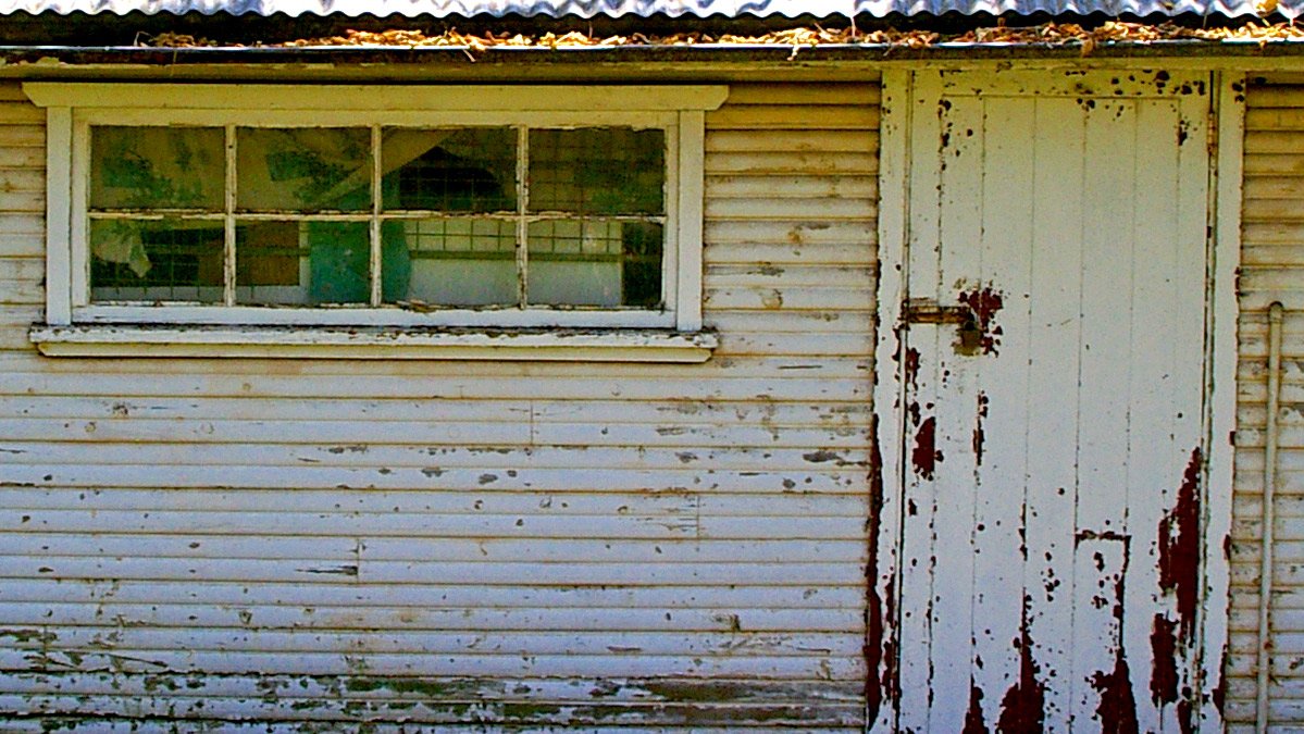 an old house with a broken window and rusty siding
