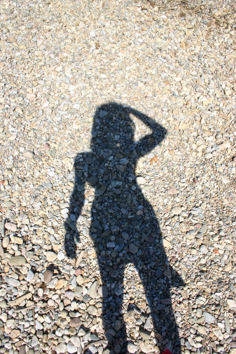 the shadow of a woman on the rocks of the ground