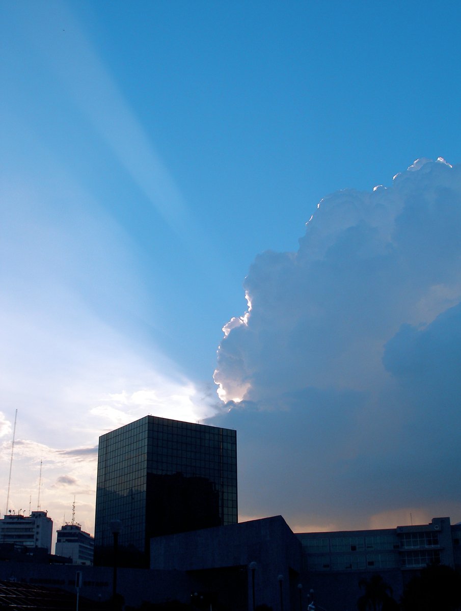 a large cloud looms over buildings in the sky