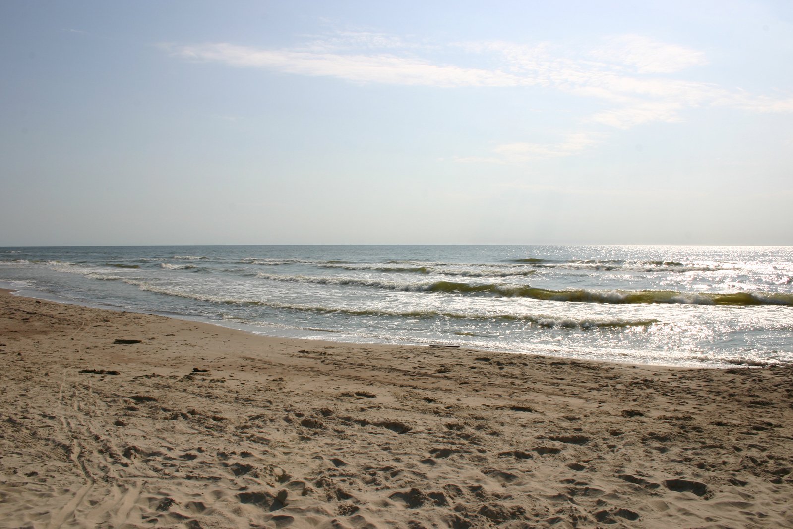 the sky is partly cloudy over the water and beach