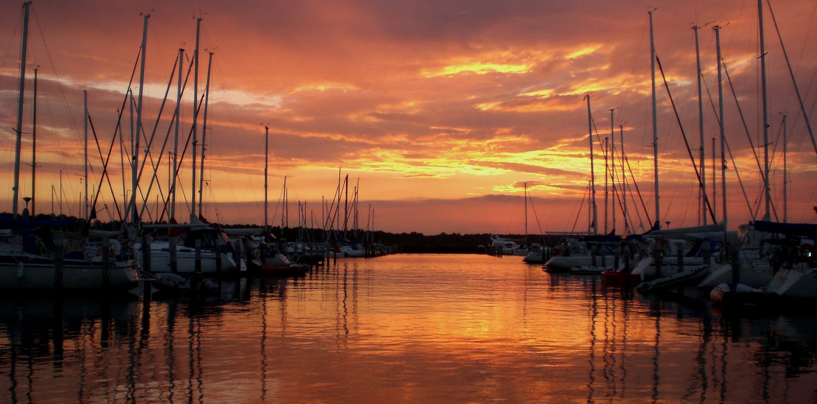 a red sky at sunset over a harbor filled with docked boats