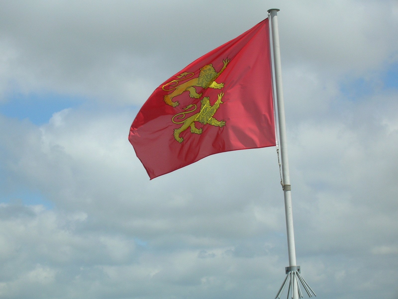 a very large flag flying high on top of a cloudy sky