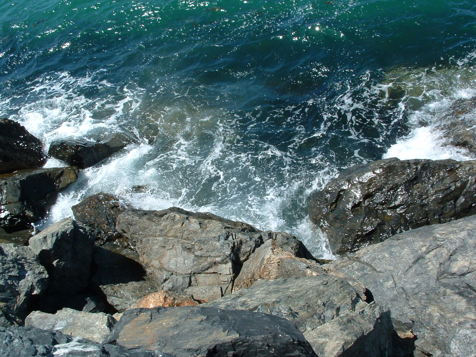 waves crashing over the rocks next to the water