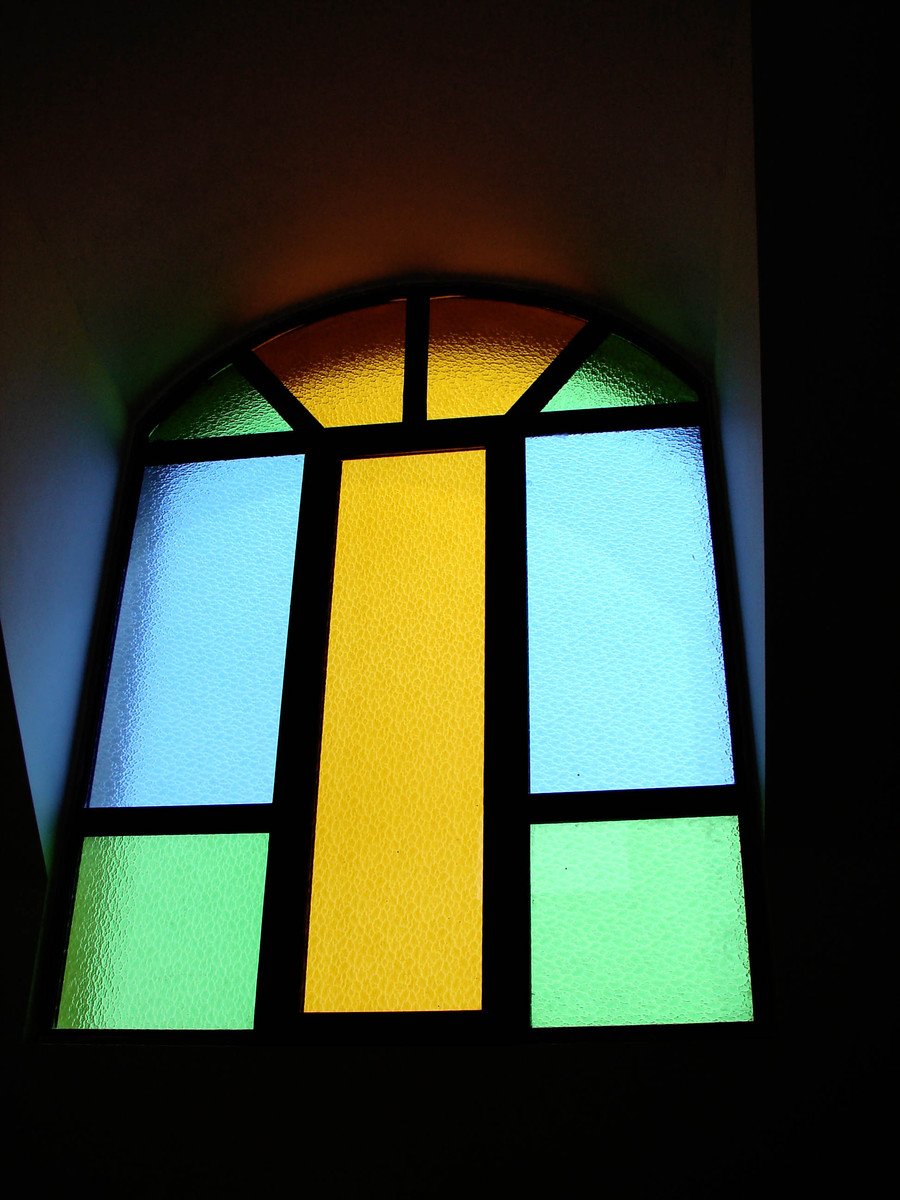 a multicolored glass window with a cross in the center