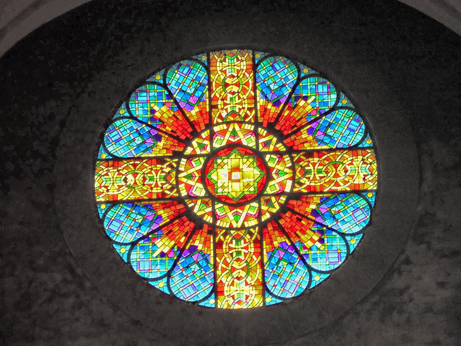 the cross of stain glass is displayed in the center of the building