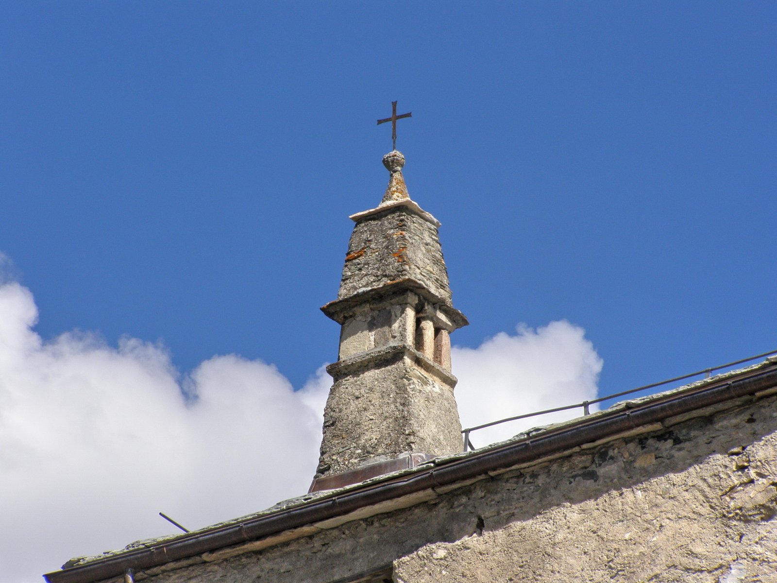 a church steeple with a cross on it, against a blue sky