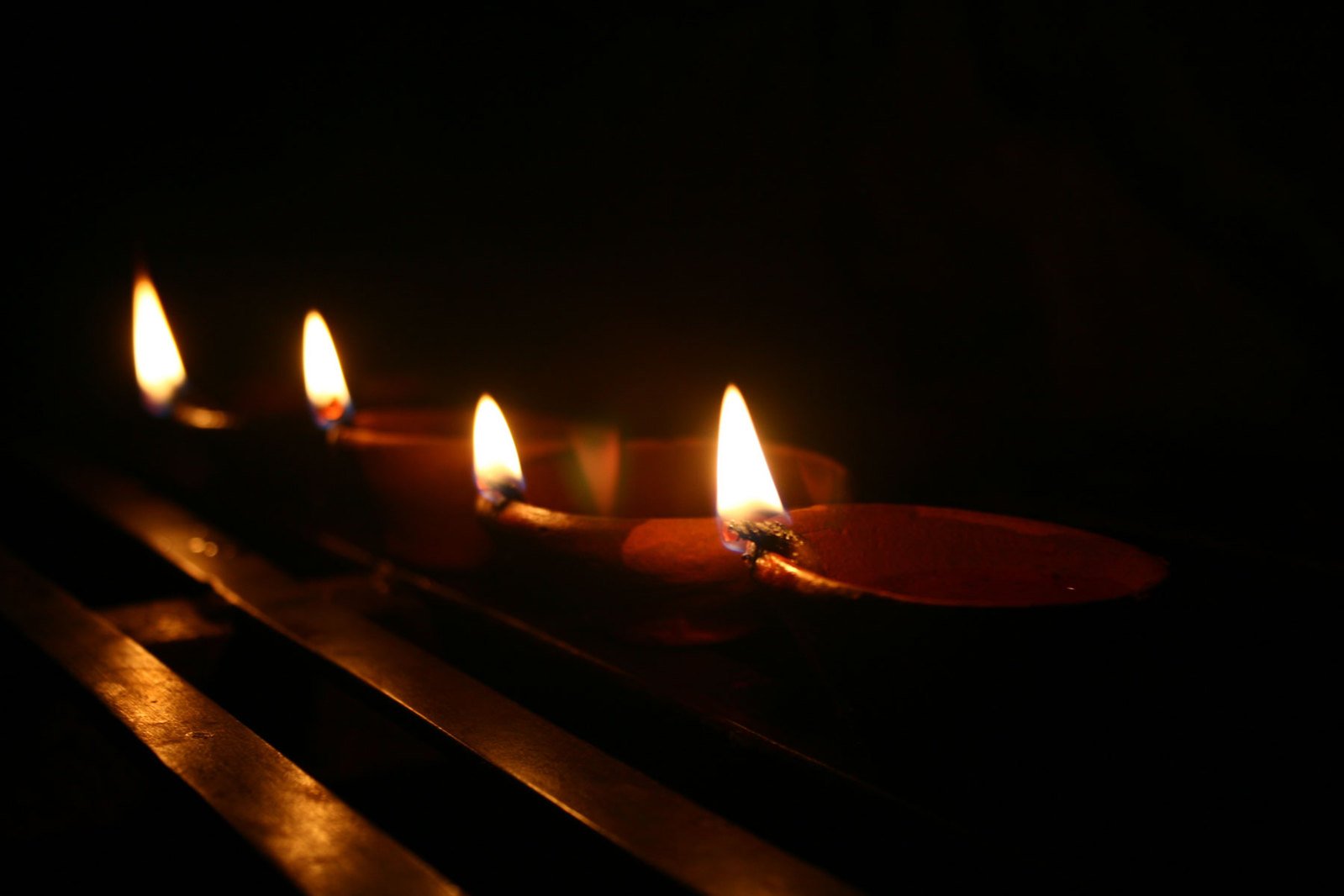 four candles light up on a table in the dark