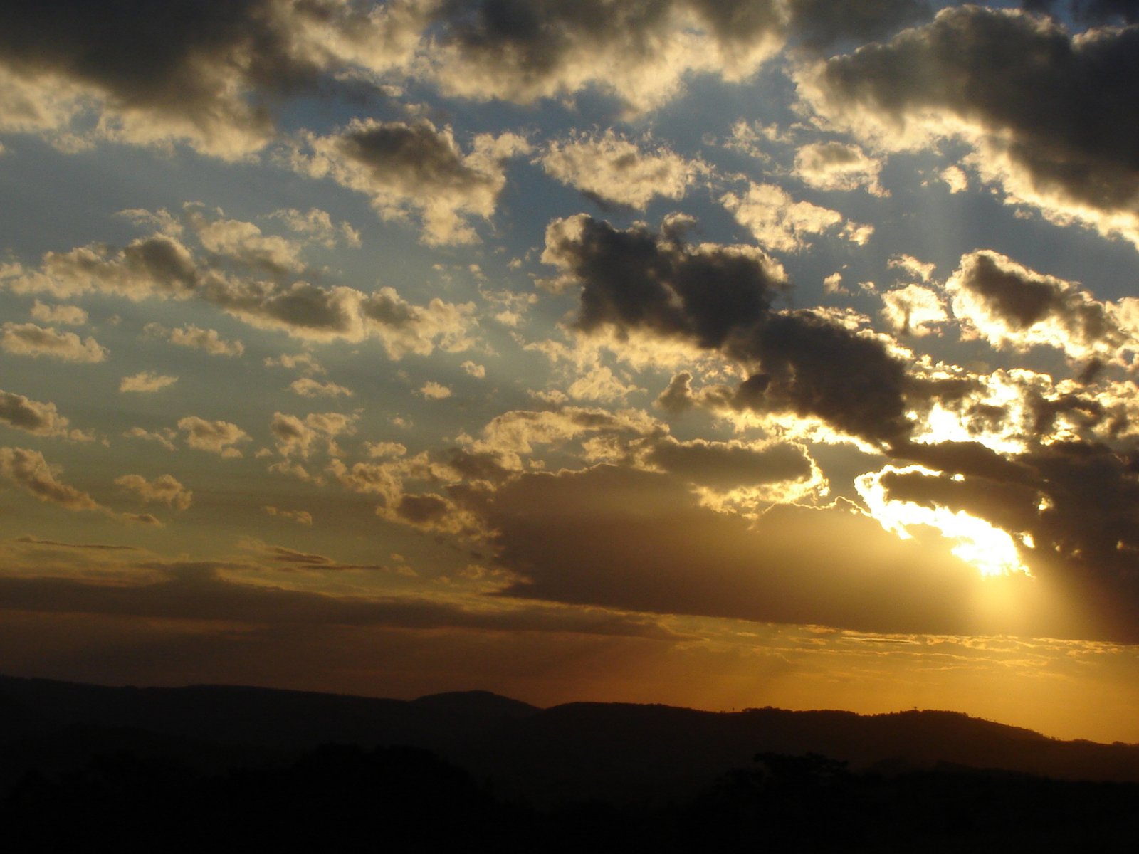 a sunset is seen through clouds over mountains